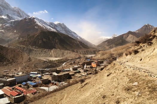 View from the trail onto the town of Manang, the valley leading to Tilicho can be seen in the background, underneath a cloud of dust, Annapurna Circuit Trek, Nepal 2022
