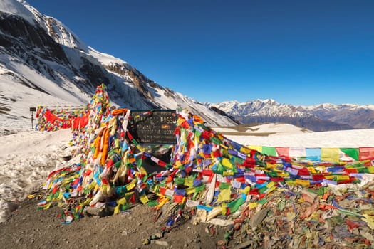 The sign on the highest point of the Thorong, Thorung, Thorang La pass, covered by hundreds of colorful prayer flags, Annapurna Circuit Trek, Nepal 2022