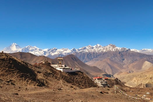 The Guru Rinpoche View Point in a hilly, dry landscape outside of the town of Muktinath in front of a snow capped mountain range with Dhaulagiri I on the left, Annapurna Circuit Trek, Nepal 2022