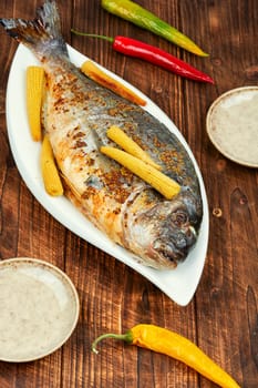 Dorado fish baked in the oven with small corn. Mediterranean diet. Delicious grilled fish. Top view