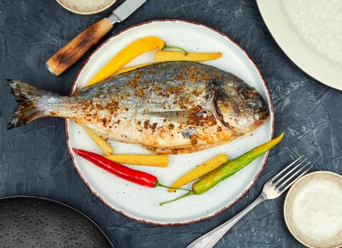 Dorado fish baked in the oven with small corn. Mediterranean diet. Delicious grilled fish. Top view