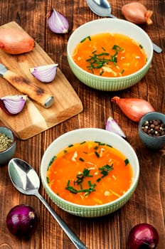 Fragrant onion soup in a ceramic bowl on a rustic wooden table.