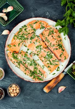 Fresh raw salmon fillet fish in garlic green marinade ready for baking.