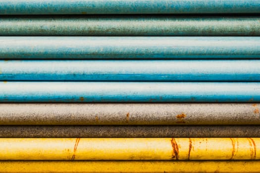 Stacked pipes, transitioning colors, blue, brown and yellow, abstract closeup shot