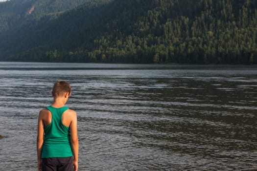 Boy on Teletskoye lake in Altai mountains, Siberia, Russia. Beauty summer day.