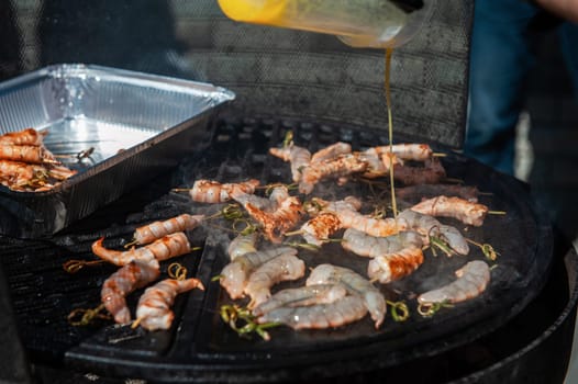 A professional cook prepares shrimps on the grill outdoor, food or catering concept