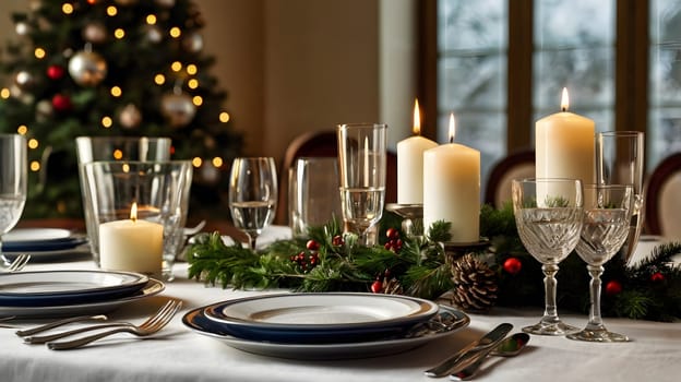 A white tablecloth with a blue-rimmed dinner plate setting sits next to a centerpiece of lit white candles, evergreen boughs, and red berries. The table is set with silver flatware and glasses filled with water. A decorated Christmas tree stands behind the table, adding a festive ambiance to the scene.