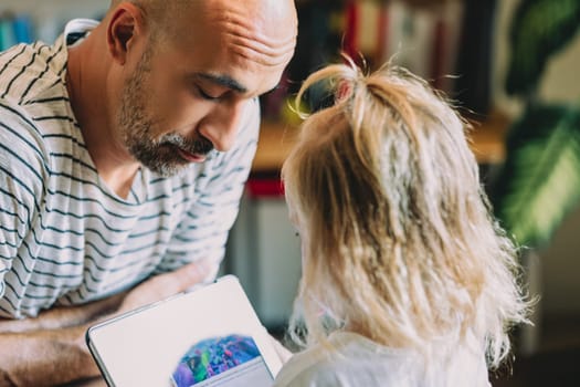 Dad and his little girl are sharing a sweet moment while using a tablet, creating a heartwarming scene of family connection and digital interaction