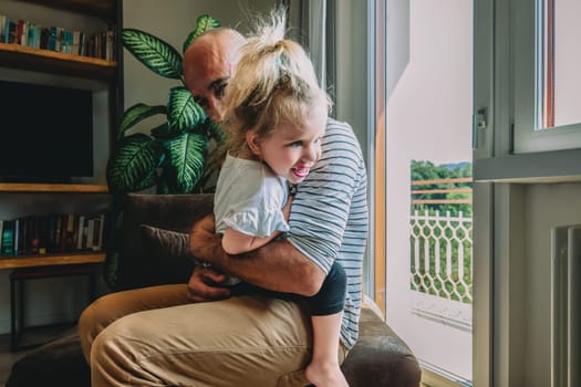 Father is embracing his young daughter, creating a heartwarming scene of love and connection. They are enjoying a peaceful moment together in their cozy living room