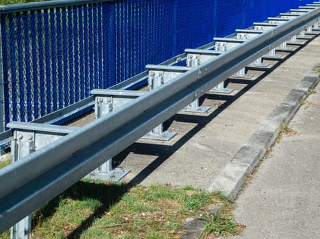 Partial perspective view of the railing with guard rails installed in front of it on a motorway bridge in summer in Bavaria.
