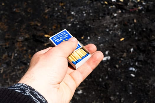 Setting fire to picnic fire . Burning matches in hands