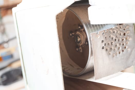 Close up of a sanding machine inside a workshop, showing the details of its components. The shallow depth of field emphasizes the texture and craftsmanship of the environment