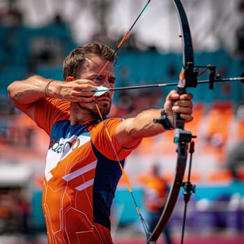 Male athlete drawing bow with intense focus during sunny day competition