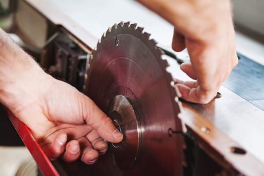 Skilled carpenter changing a table saw blade in his workshop, preparing for woodworking with precision and focus on safety. Sawdust fills the air as he transforms wood into craftsmanship