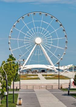 Baku, Azerbaijan - May 4, 2024: A view of the Baku Eye Ferris Wheel, located beside Deniz Mall. The wheel is in the background with few people walking in the foreground.