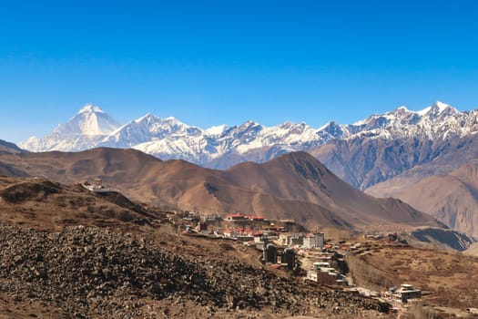 View onto the town of Muktinath, Ranipauwa and the Guru Rinpoche View Point in front of a snow capped mountain range with Dhaulagiri I on the left, Annapurna Circuit Trek, Nepal 2022