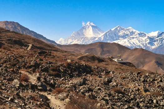 The Guru Rinpoche View Point in the hilly, rocky, dry landscape outside of Muktinath in front of a snow capped mountain range with Dhaulagiri I on the left, Annapurna Circuit Trek, Nepal 2022