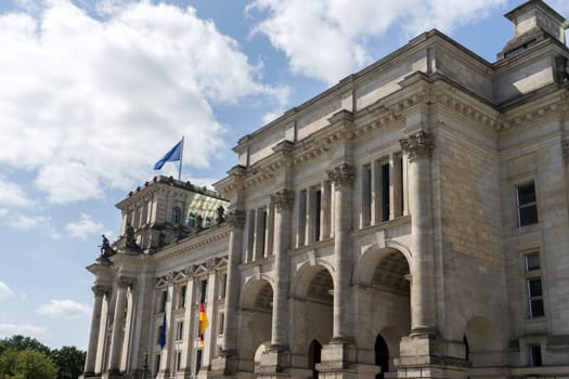 Detailed shot of the Berlin Reichstag against a blue sky with white clouds
