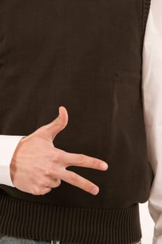 A male hand held in front of the stomach symbolizes the number 3 with the fingers.