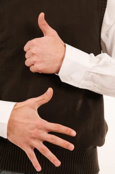A male hand held in front of the stomach symbolizes the number 6 with the fingers.
