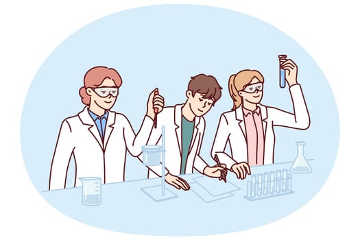 Students conduct experiments in laboratory doing scientific research to prepare for chemistry exam. Guys and girls in white coats stand at laboratory table with flasks filled with chemical reactions.