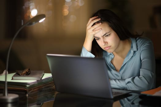 Frustrated businesswoman working online with a laptop in the night at home