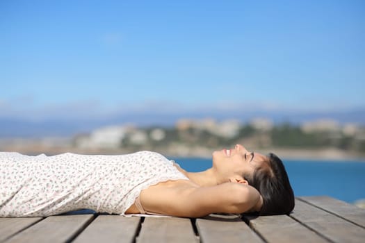 Profile of a happy woman wearing dress sunbathing on the beach a sunny summer day
