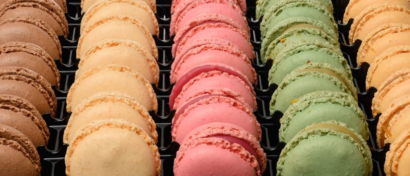 Multi-colored macarons in a plastic box, top view. Assortment
