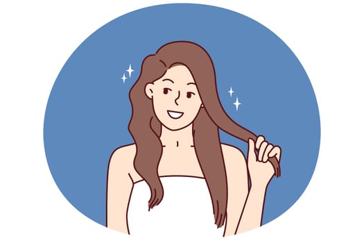 Beautiful girl fixes hair enjoying silky hairstyle after using new herbal shampoo with firming agents. Positive woman in white towel with shiny hair smiling and looking at screen after haircare