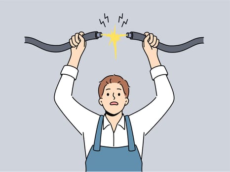 Man electrician connects high-voltage wire to electrify building, risking electric shock due to safety violation. Master electrician works taking care of continuous supply of electricity to people