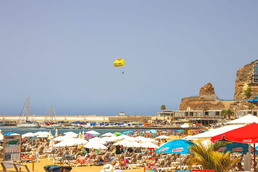 Gran Canaria, Spain, Canary Islands, Puerto Rico - Jul 18, 2024. The Playa de Porto Rico beach with a lot of tourists.