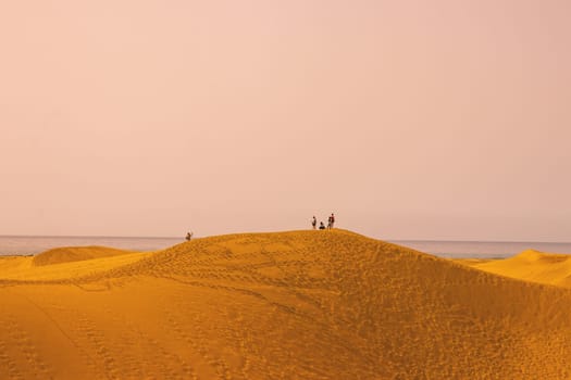 Gran Canaria, Spain, Canary Islands, Playa del Inglés - Jul 17, 2024. Tourists walking in the fine sand dunes of Maspalomas. Maspalomas Dunes Nature Reserve.