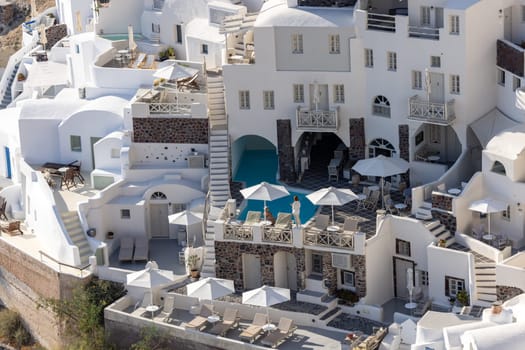 Oia, Santorini, Greece - June 28, 2021: Whitewashed houses with terraces and pools and a beautiful view in Oia on Santorini island, Greece
