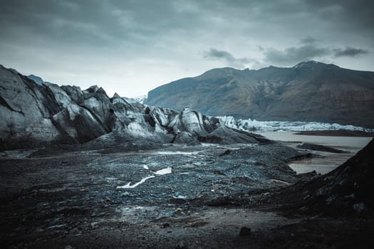 VATNAJOKULL Melting glacier ice creates a stream flowing through dark volcanic earth
