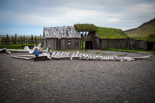 Two children playing  whale skeleton  reconstructed viking settlement Iceland