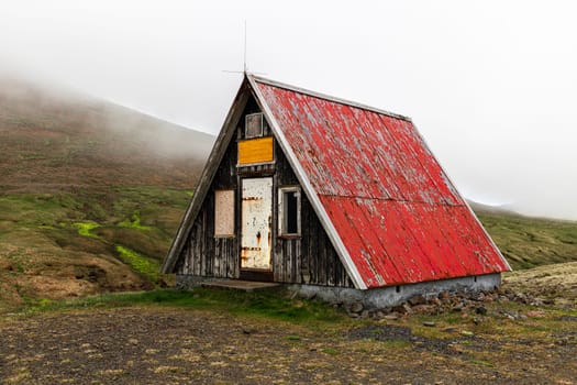 Old abandoned wooden hut red roof  mountain background.Iceland