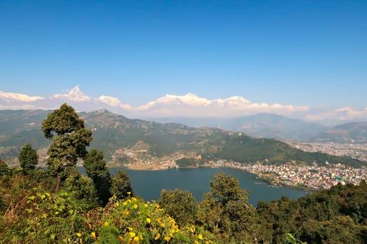 View onto Phewa Lake, the town of Pokhara and the mountain range rising behind it, with Mount Machapuchare on the left, on the way up to the World Peace Pagoda, Pokhara, Nepal 2022