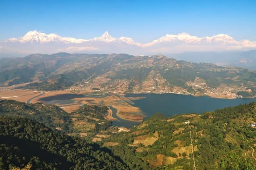 View onto Phewa Lake in front of a mountain range with Mount Machapuchare in the middle, on the way up to the World Peace Pagoda close to Pokhara, Nepal 2022