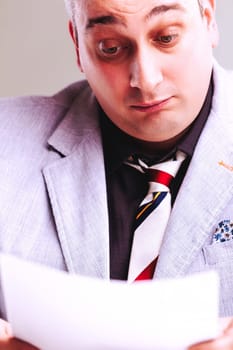 Cunning salesman is holding and reading a contract with a suspicious expression, plotting how to deceive someone for his own profit