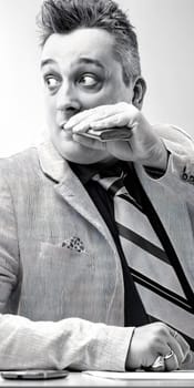 Businessman holding a flask near his mouth while looking away with a worried expression issues of alcoholism in the workplace