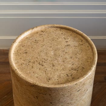 High angle close-up of a round marble side table. The table has a sleek marble surface and a minimalist frame