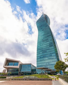 SOCAR Tower, a striking glass skyscraper rises in Baku, Azerbaijan, showcasing its unique twisted design against a backdrop of fluffy clouds