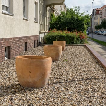 Front garden without plants with pebbles and empty terracotta pots in summer
