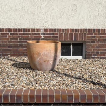Front garden without plants with pebbles and empty terracotta pot in summer