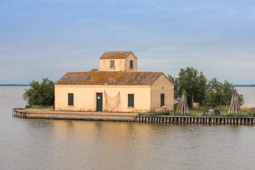 Comacchio, Italy - 13 June 2024. Casone Donnabona, traditional house for fishermen in lagoon. Wetland, blue sky.