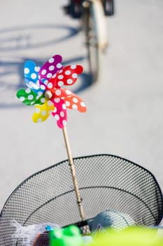 Colorful pinwheel attached to bicycle basket to entertain toddler child riding on front child seat on bike in summer