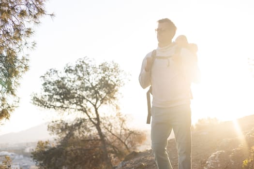 Young father carrying his infant baby boy son in backpack while tracking around Malaga, Spain in sunset. Family travel and vacation concept.