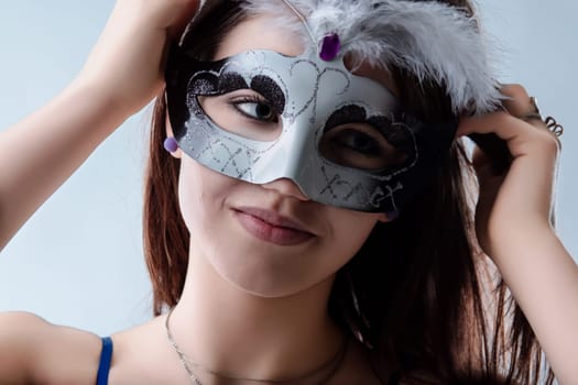 Young woman adjusts her venetian carnival mask, ready for a night of mystery and celebration, smiling with excitement