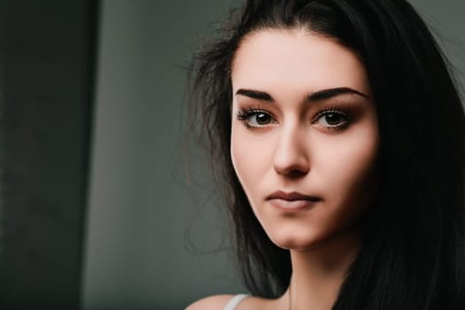 Portrait of a young woman with long black hair, conveying a sense of contemplation and introspection with her serious expression