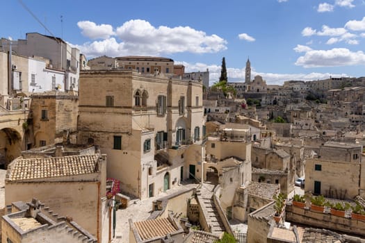 Italy, Matera - May 22, 2024: Panoramic view from Luigi Guerricchio Belvedere of historic city carved in rock Sassi of Matera. Bell tower of Matera Cathedral in a distance